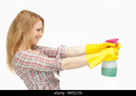 Fair-haired woman holding a spray bottle while smiling against white background Stock Photo