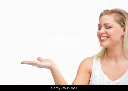 Cheerful woman placing her hand palm up against a white background Stock Photo