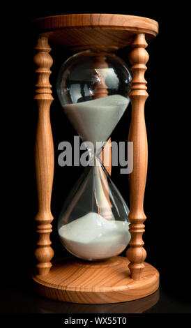 Sand flowing inside of hourglass against a black background Stock Photo