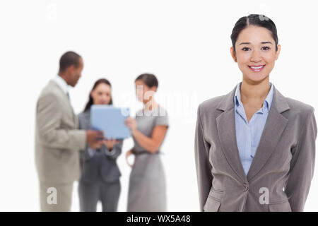 Businesswoman smiling with co-workers watching a laptop in the background Stock Photo