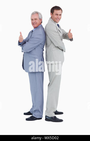 Tradesmen standing back to back giving thumbs up against a white background Stock Photo