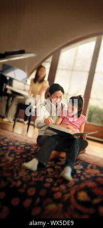 A mother smiles as she teaches her daughter in the house. Stock Photo