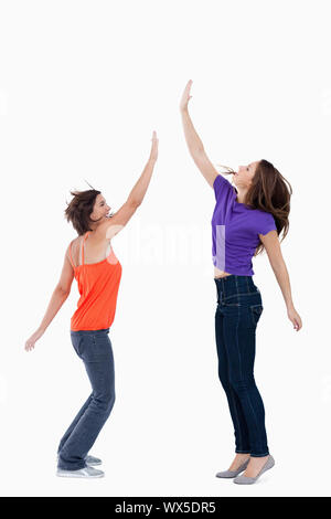 Smiling teenager standing on the tips of her toes while her friend is trying to touch her hand Stock Photo