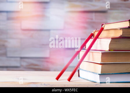 stack of books and two red wooden pencils on wooden background, back to school concept Stock Photo