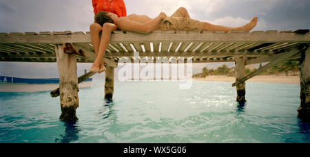 Low angle view of a couple relaxing on a pier. Stock Photo