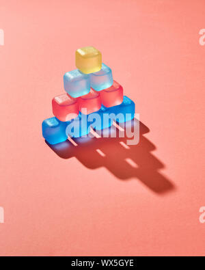 Creative pyramid from colored plastic cubes with liquid, shadows on a background in a color of the year 2019 Living Coral Panton Stock Photo