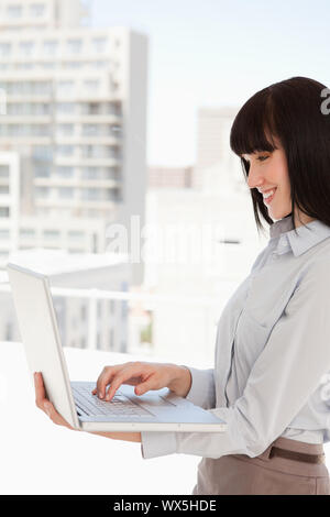 Woman smiling as she uses her laptop on the couch, side view Stock ...