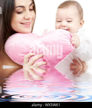happy baby and mama with heart-shaped pillow in water Stock Photo