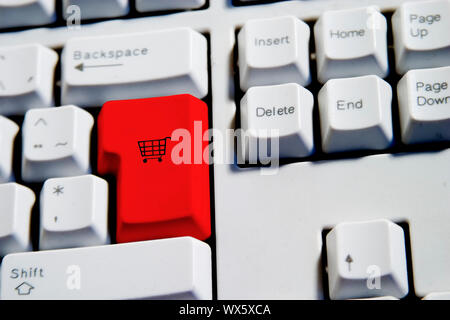 Computer Keyboard from a desktop computer with the enter key highlighted in Red with a small shopping cart on it Stock Photo