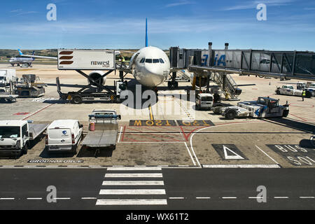 Madrid, Spain - 12 May 2019: runway with airplanes and service stuff and cars on the sunny sky background in international airport. Editorial. Horizon Stock Photo