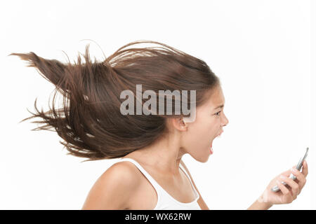 Screaming angry woman on the mobile phone. Dynamic and energetic image of young mixed race chinese / caucasian woman isolated on seamless white backgr Stock Photo