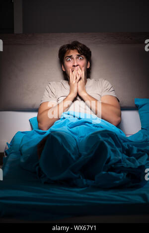 Young man scared in his bed having nightmares Stock Photo