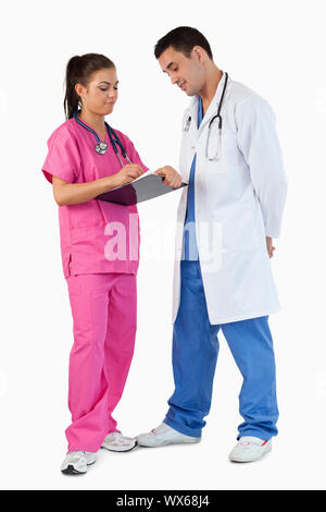 Portrait of a doctor talking while his intern is taking notes against a white background Stock Photo