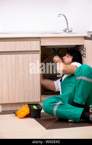 Young plumber repairing wash basin at kitchen Stock Photo