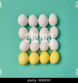 Pattern in the form of a square of painted yellow and white eggs on a green background with copy space. Billiard game concept. F Stock Photo