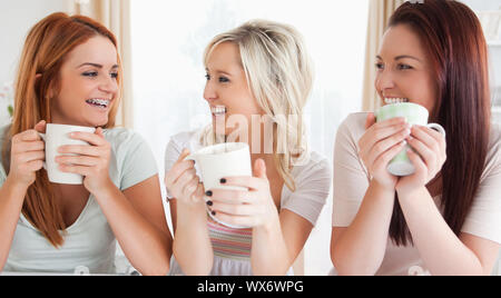 Young Women sitting at a table with cups in a kitchen Stock Photo