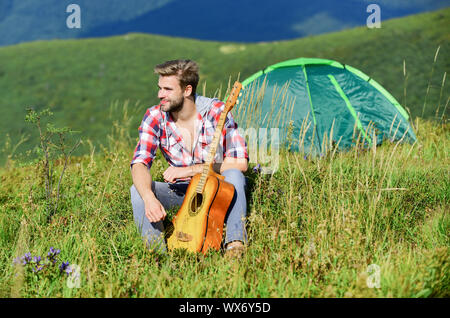 Dreamy wanderer. Pleasant time alone. Peaceful mood. Guy with guitar contemplate nature. Wanderlust concept. Inspiring nature. Musician looking for inspiration. Summer vacation highlands nature. Stock Photo
