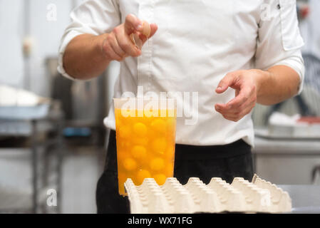 Pastry Chef breaking eggs to prepare the cake Stock Photo