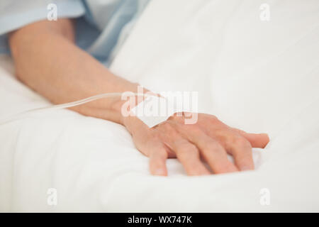 Hand with intravenous drip in hospital bed Stock Photo