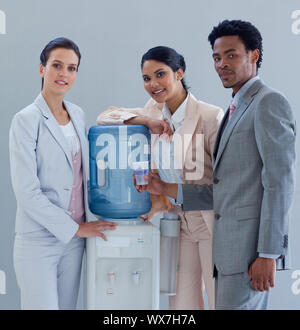Business people speaking next to a water cooler in office Stock Photo