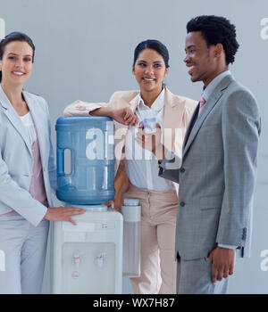 Business people speaking next to a water cooler in office Stock Photo