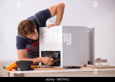 Young handsome contractor repairing fridge Stock Photo