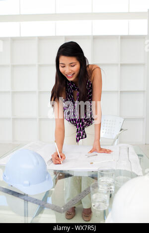 Portrait of a female architect studying plans in the office Stock Photo