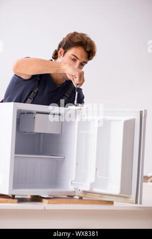 Young handsome contractor repairing fridge Stock Photo