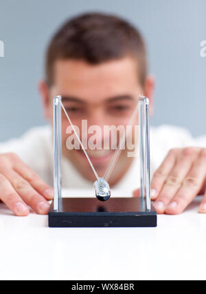 Businessman looking at pendulum balls in office Stock Photo