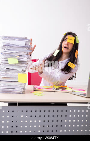 Young female employee in conflicting priorities concept Stock Photo