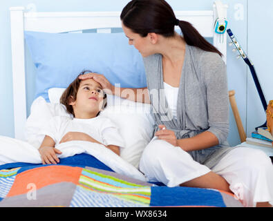Mother taking her son's temperature lying in bed Stock Photo