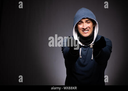 Young gangster in hood on grey background Stock Photo