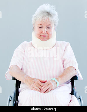 Upset senior woman with a neck brace sitting on a wheelchair in a hospital Stock Photo