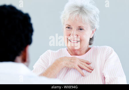 Smiling senior patient sitting on a wheelchair talking with her doctor in a hospital Stock Photo