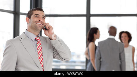 Handsome businessman on phone in office with his team Stock Photo