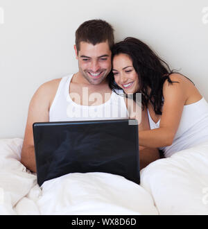 Delighted couple using a laptop in the bedroom Stock Photo