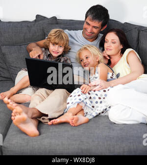 Smiling family using a laptop on a sofa Stock Photo