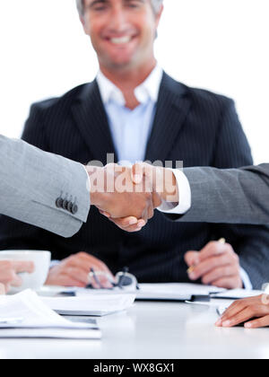 Close-up of a handshake between two businesspeople in front of the boss in the office Stock Photo