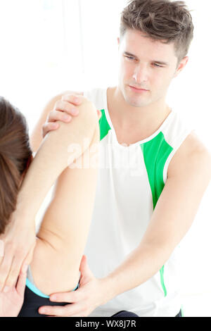 Confident physical therapist checking a woman's shoulder during a medical exam Stock Photo