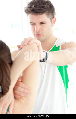 Concentrated physical therapist checking a woman's shoulder during a medical exam Stock Photo