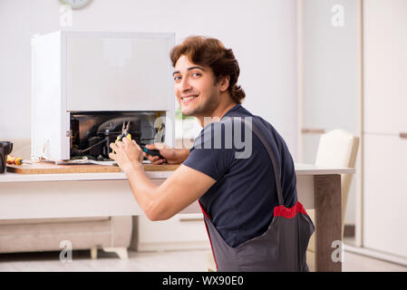Young handsome contractor repairing fridge Stock Photo
