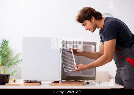 Young handsome contractor repairing fridge Stock Photo
