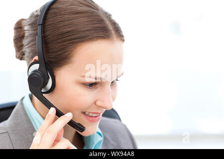 Female operator on the phone with earpiece sitting in her office Stock Photo