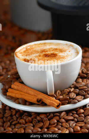 Cup of cappuccino  with cinnamon and spilled out coffee beans. Stock Photo