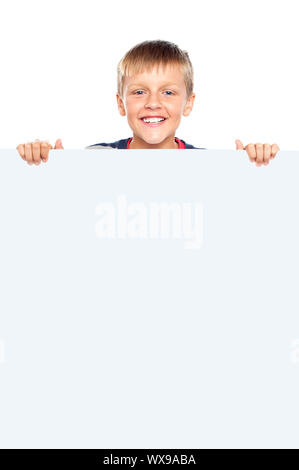 Young boy hiding behind big whiteboard ad. Business concept Stock Photo