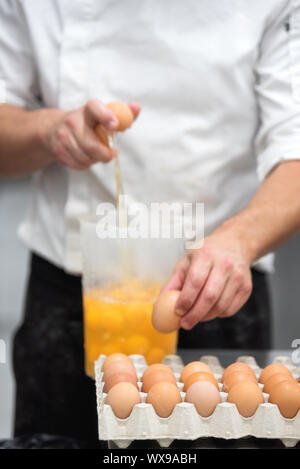 Pastry Chef breaking eggs to prepare the cake Stock Photo