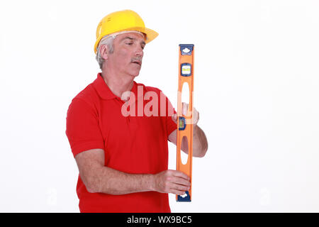 Grey-haired man holding spirit-level Stock Photo