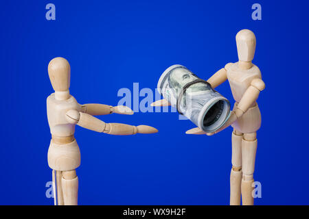 Wooden toy figures with money on blue Stock Photo