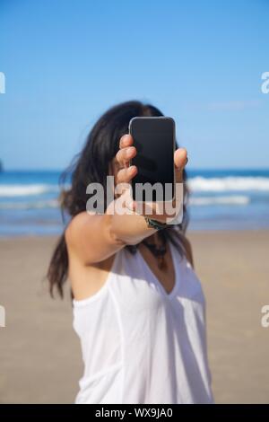 smart phone in woman hand on a beach in Asturias Spain Stock Photo