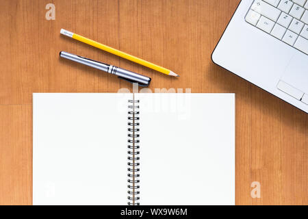 Blank notebook and computer with pen and pencil on wood table, business concept Stock Photo